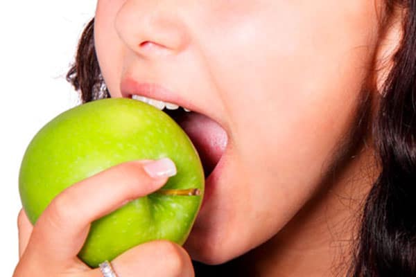Mujer mordiendo una manzana verde