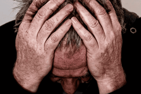 Hombre cubriéndose la cabeza con sus manos a causa del estrés